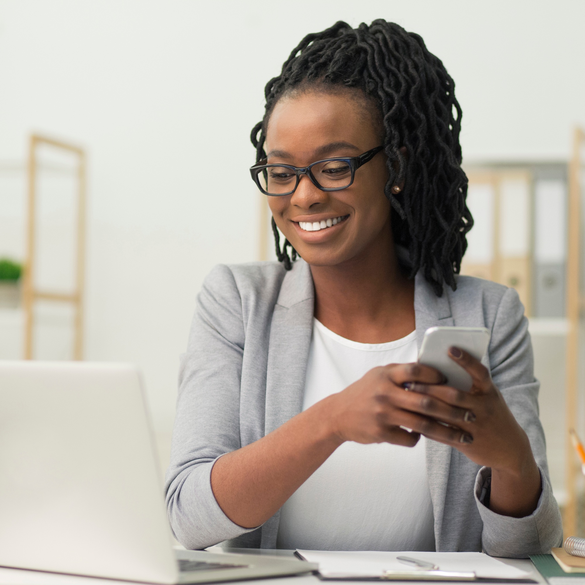 Afro Businesswoman Texting Via Smartphone Sitting In Modern Office